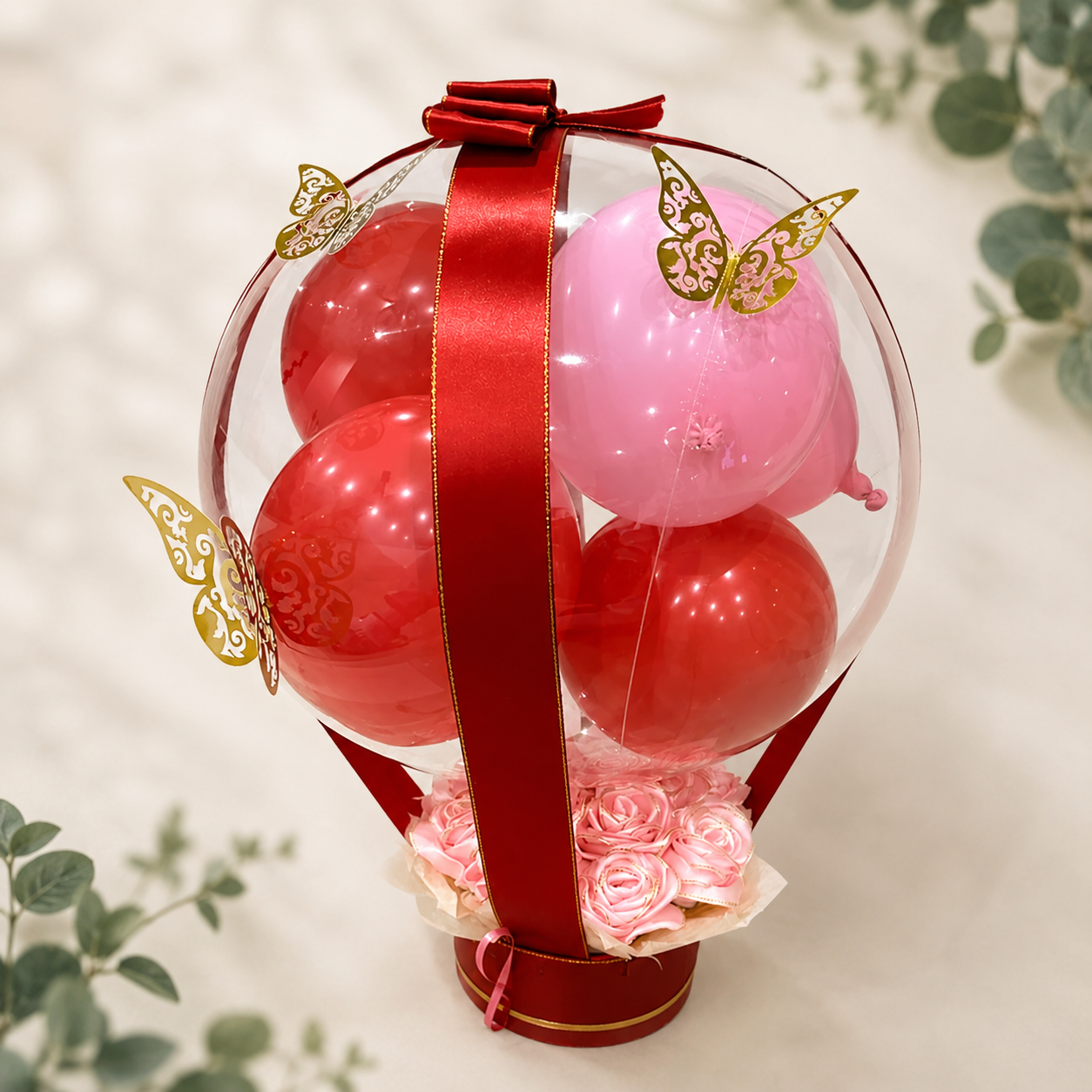 Bubble-Ballon mit roten und rosa Ballons, Rosensockel und goldenen Schmetterlingen