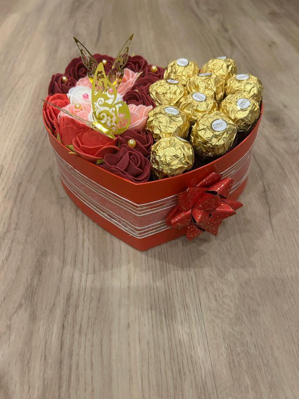 Herzbox mit Organzaband und roter Schleife, gefüllt mit Seifenrosen und Ferrero Rocher