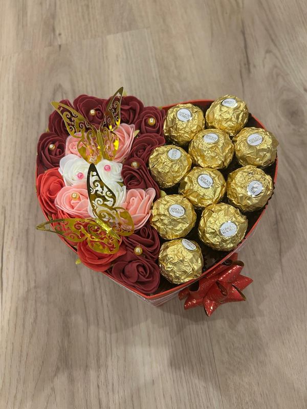 Herzförmige rote Box mit Seifenrosen in Bordeaux, Rosé und Weiß, gefüllte Hälfte mit Ferrero Rocher