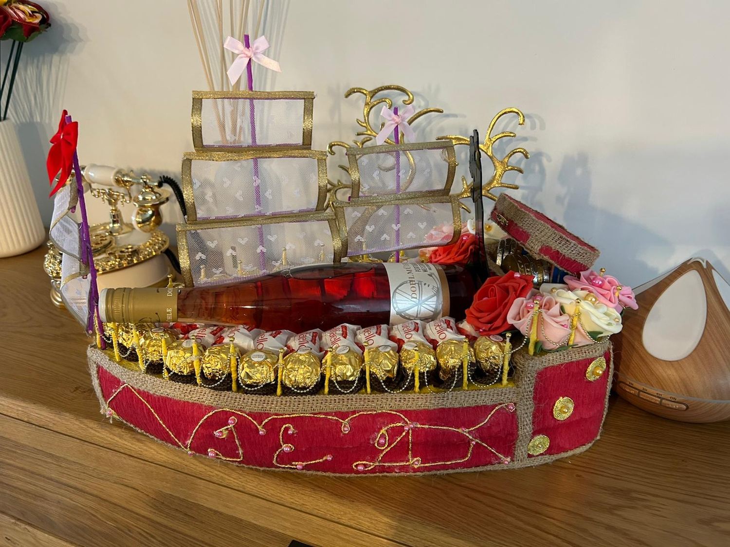 Fertiges Geschenkschiff mit Segeln aus Tüll, goldenen Bordüren und Ferrero Rocher an Deck